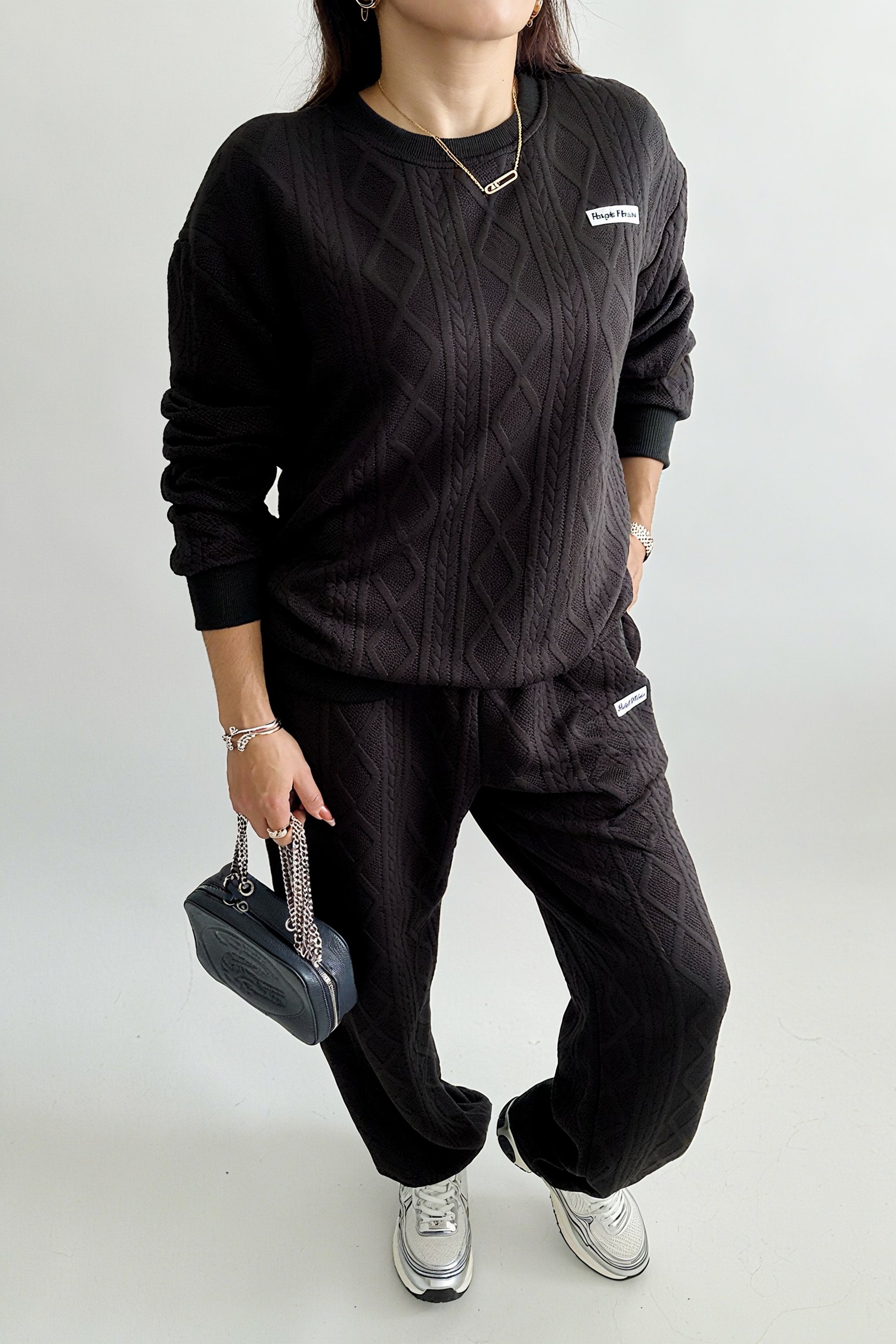 Ensemble femme 2 pièces composé d’un sweat-shirt texturé à manches longues et d’un pantalon assorti, disponible en blanc et noir, style décontracté et élégant.