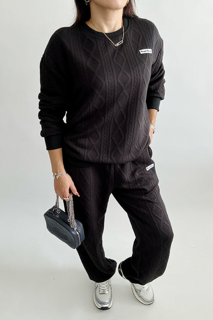 Ensemble femme 2 pièces composé d’un sweat-shirt texturé à manches longues et d’un pantalon assorti, disponible en blanc et noir, style décontracté et élégant.